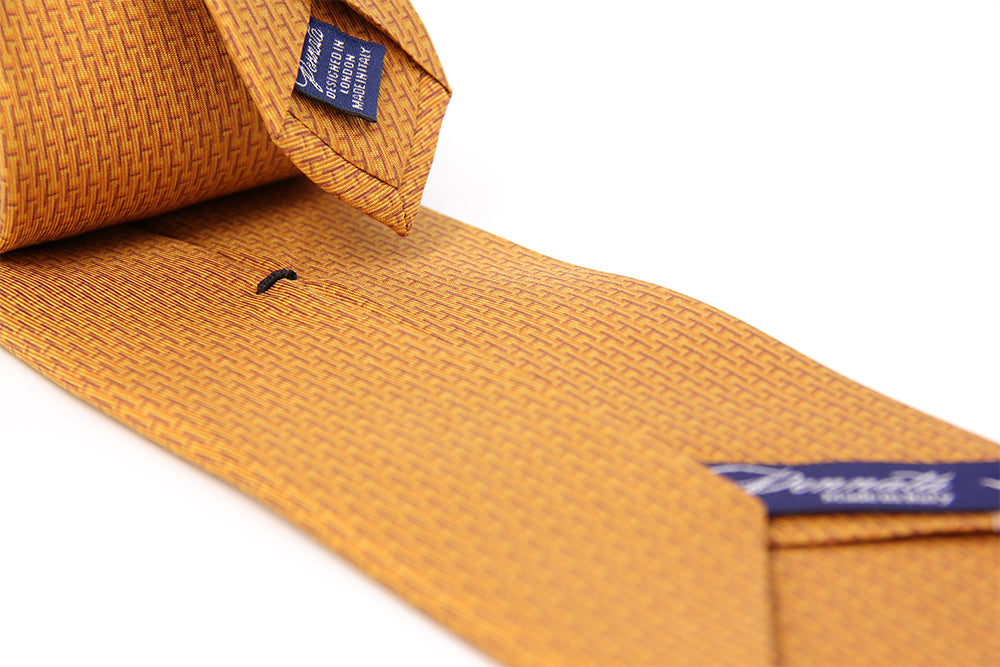 Closeup of a pattern of an orange designers silk tie