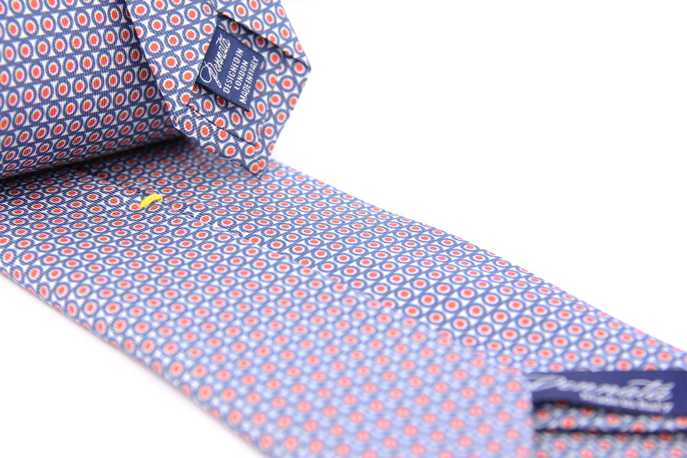 A purple tie with a geometric pattern of circles and dots on a white background, displayed in a folded and unfolded configuration.