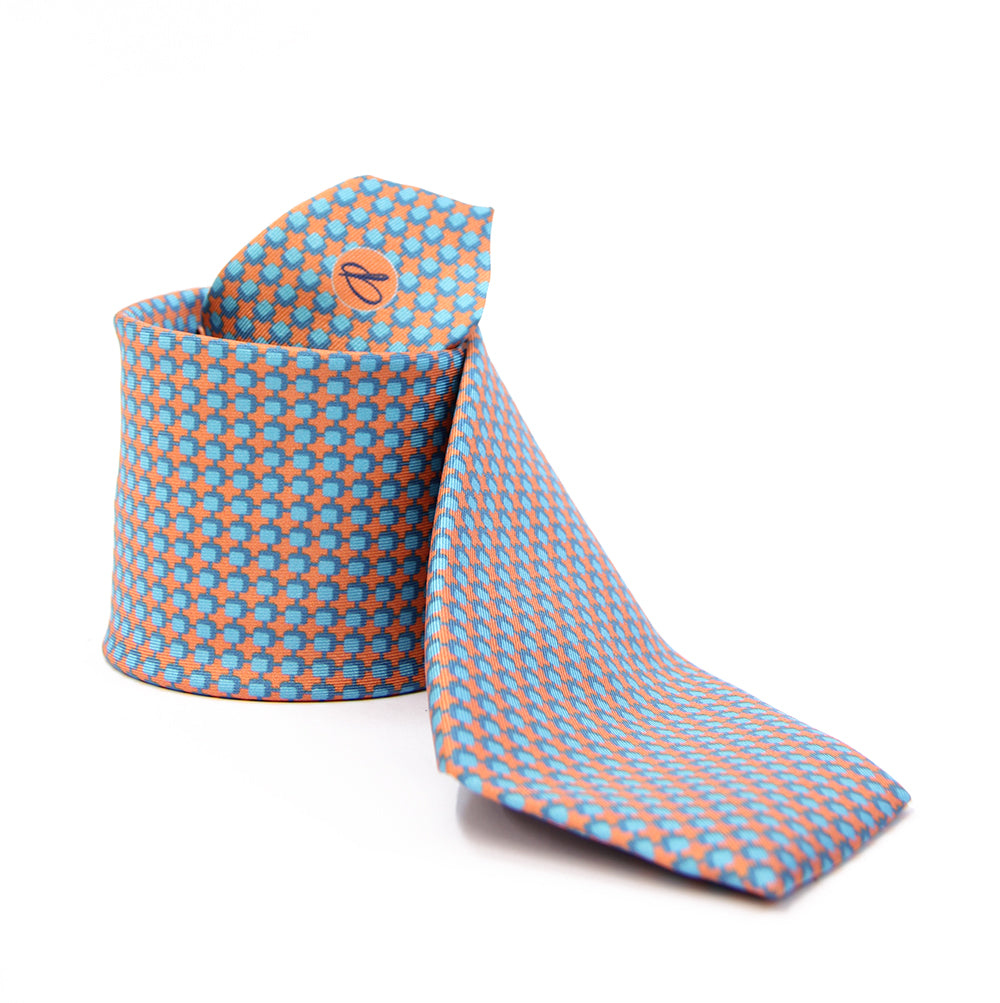 A patterned silk tie with a combination of peach and blue colors, displayed in a folded and unfolded configuration.