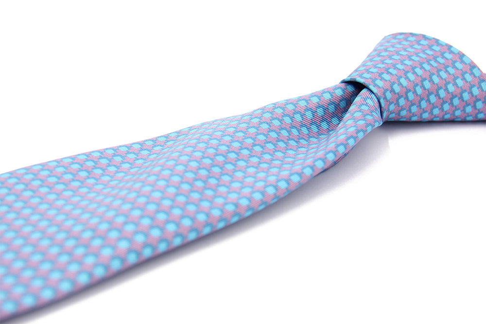 A patterned silk tie with a combination of violet and blue colors, displayed in a folded and unfolded configuration.