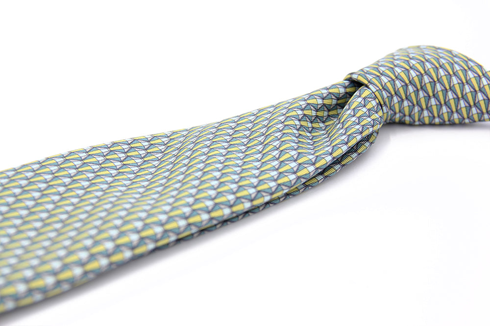 A silk tie with a geometric pattern in green and white colors, displayed on a white background.