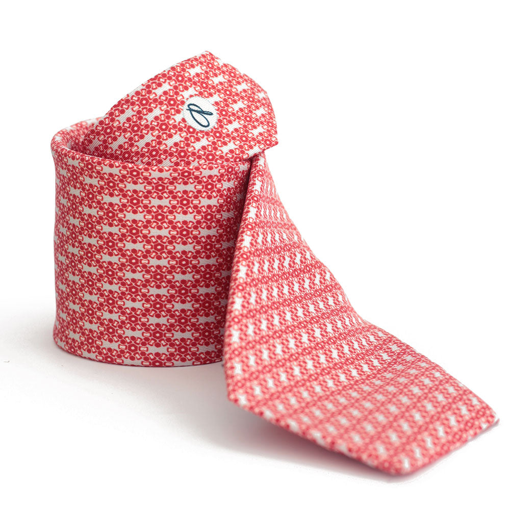 A silk tie with a red and white geometric pattern, displayed in an unrolled and rolled state against a white background.