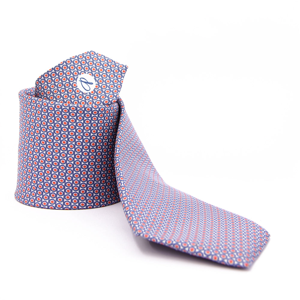 A blue tie with a geometric pattern of circles and dots on a white background, displayed in a folded and unfolded configuration.