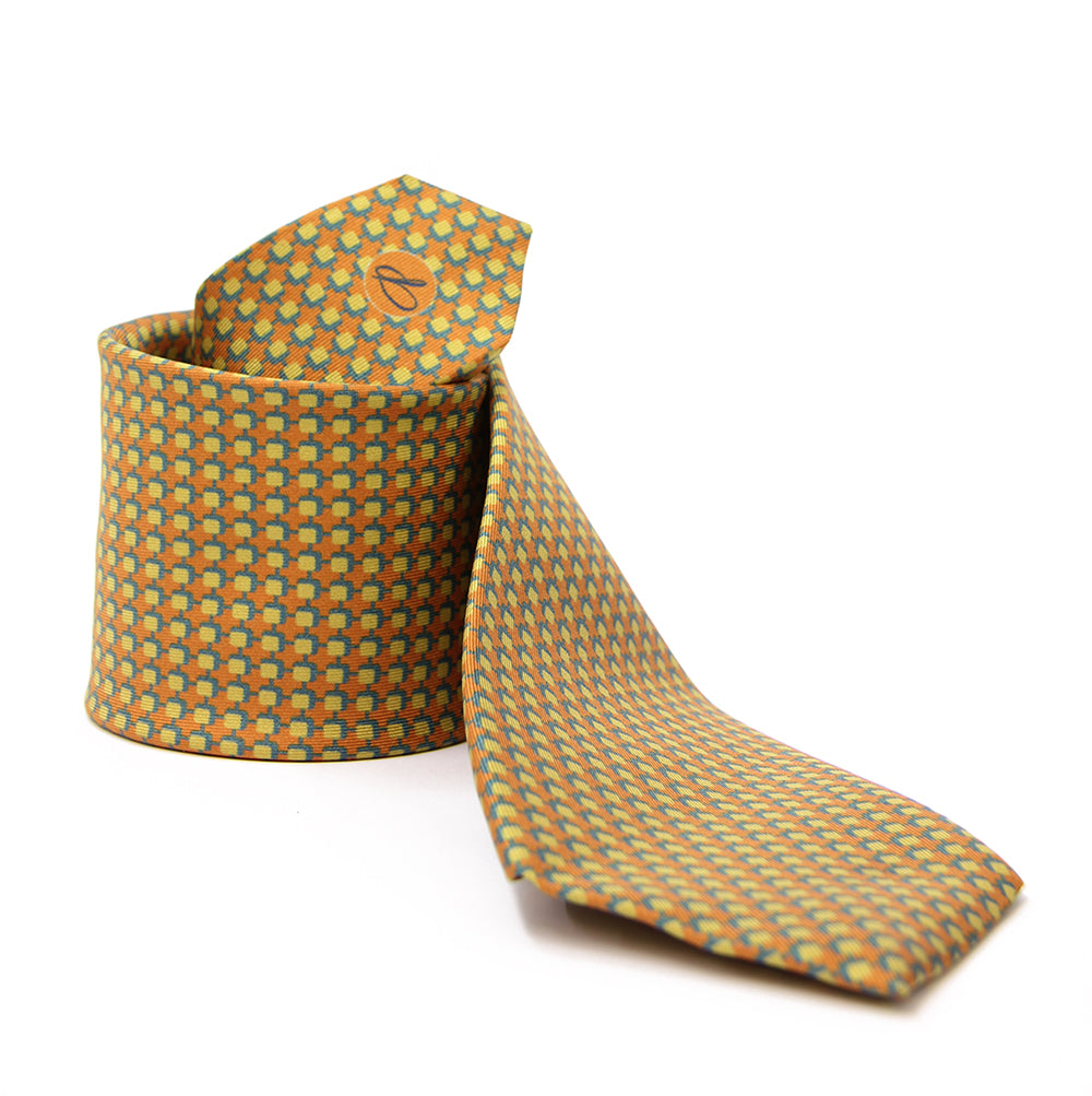 A patterned silk tie with a combination of ochre and blue colors, displayed in a folded and unfolded configuration.