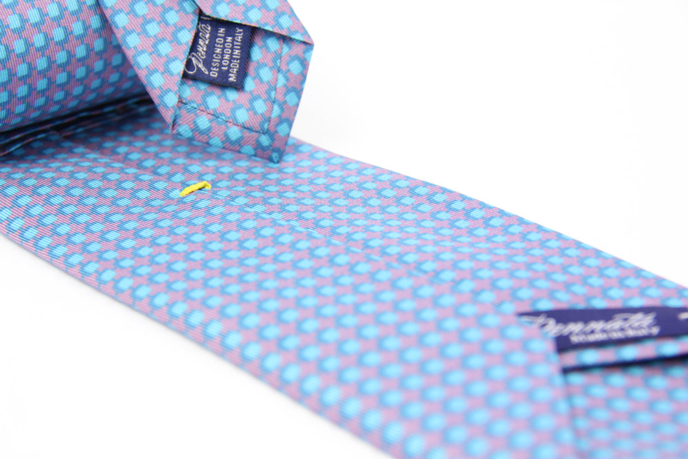 A patterned silk tie with a combination of violet and blue colors, displayed in a folded and unfolded configuration.