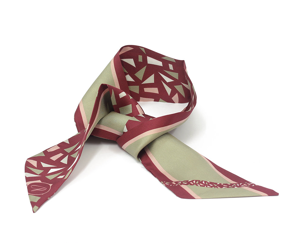 A silk twilly with a geometric pattern in burgundy and beige colors, tied in a loose knot.
