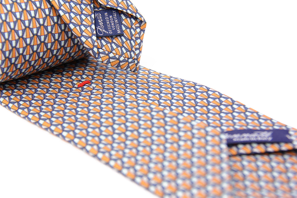 A silk tie with a geometric pattern in orange and white colors, displayed on a white background.