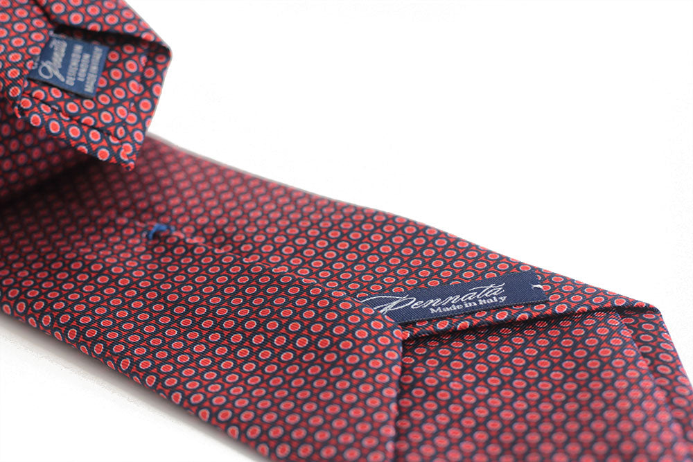 A red elegant tie with a geometric pattern of circles and dots displayed on a white background.