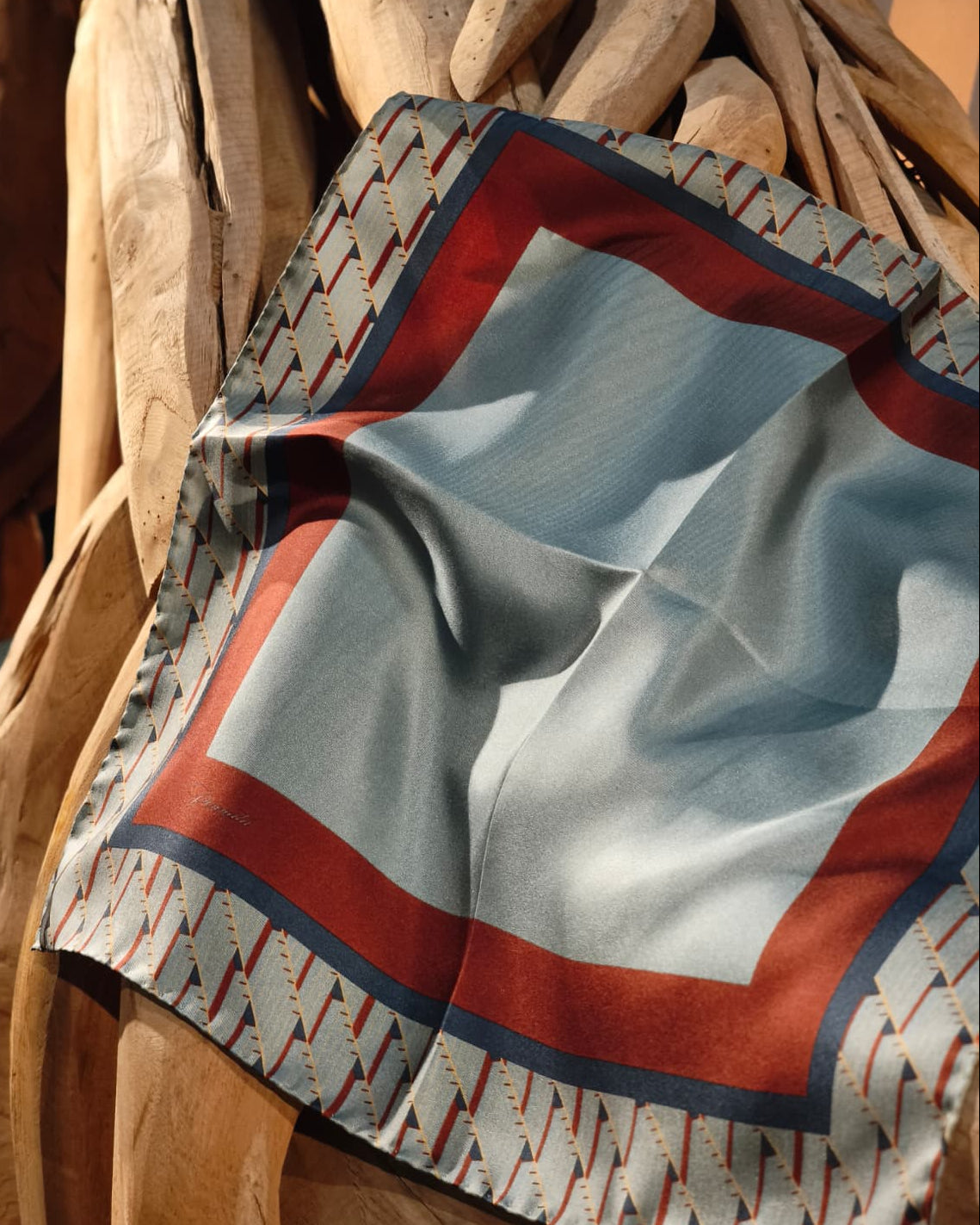 Decorative silk foulard  with geometric pattern draped over wooden furniture