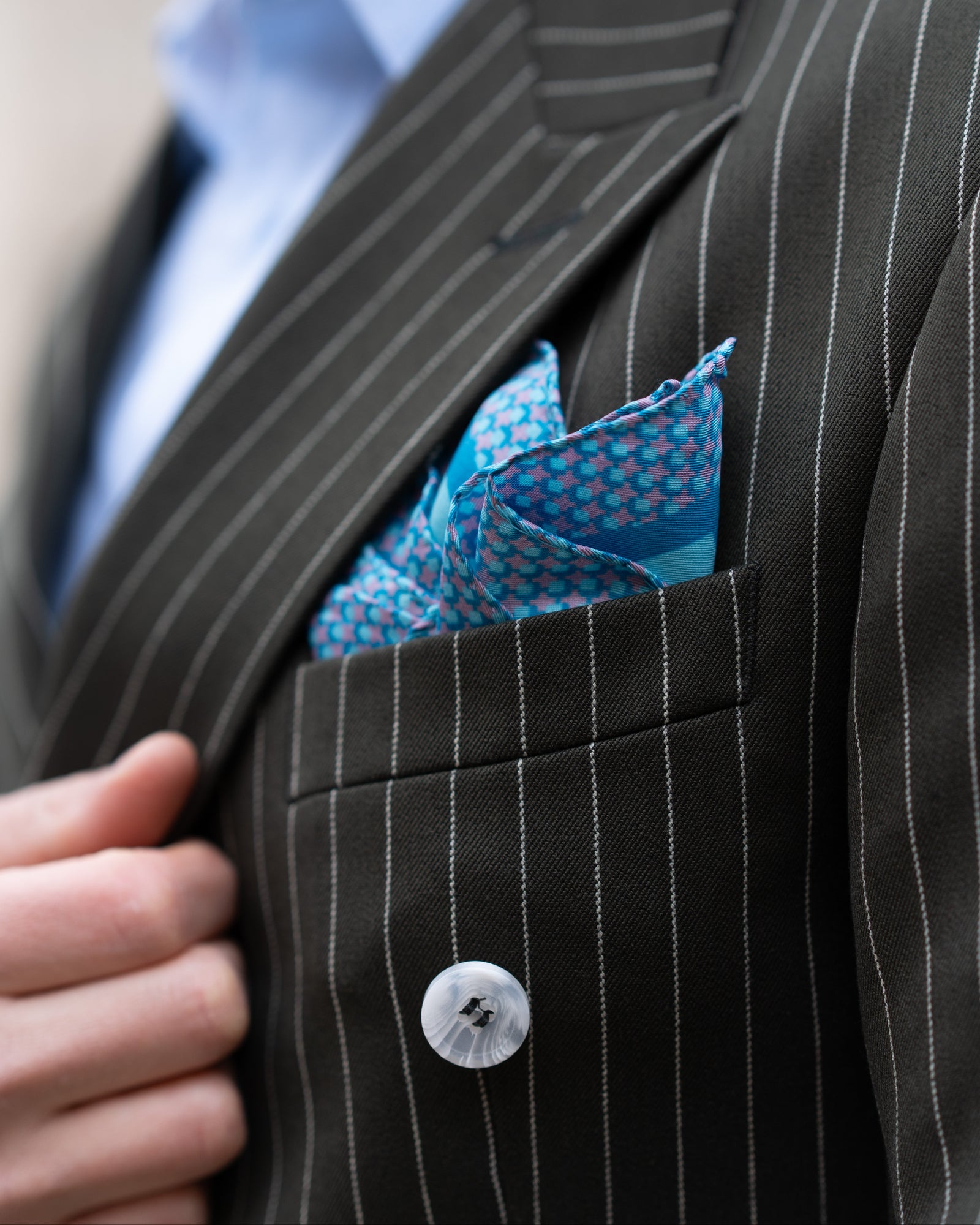 Close-up of a black pinstripe suit with a blue silk pocket square.