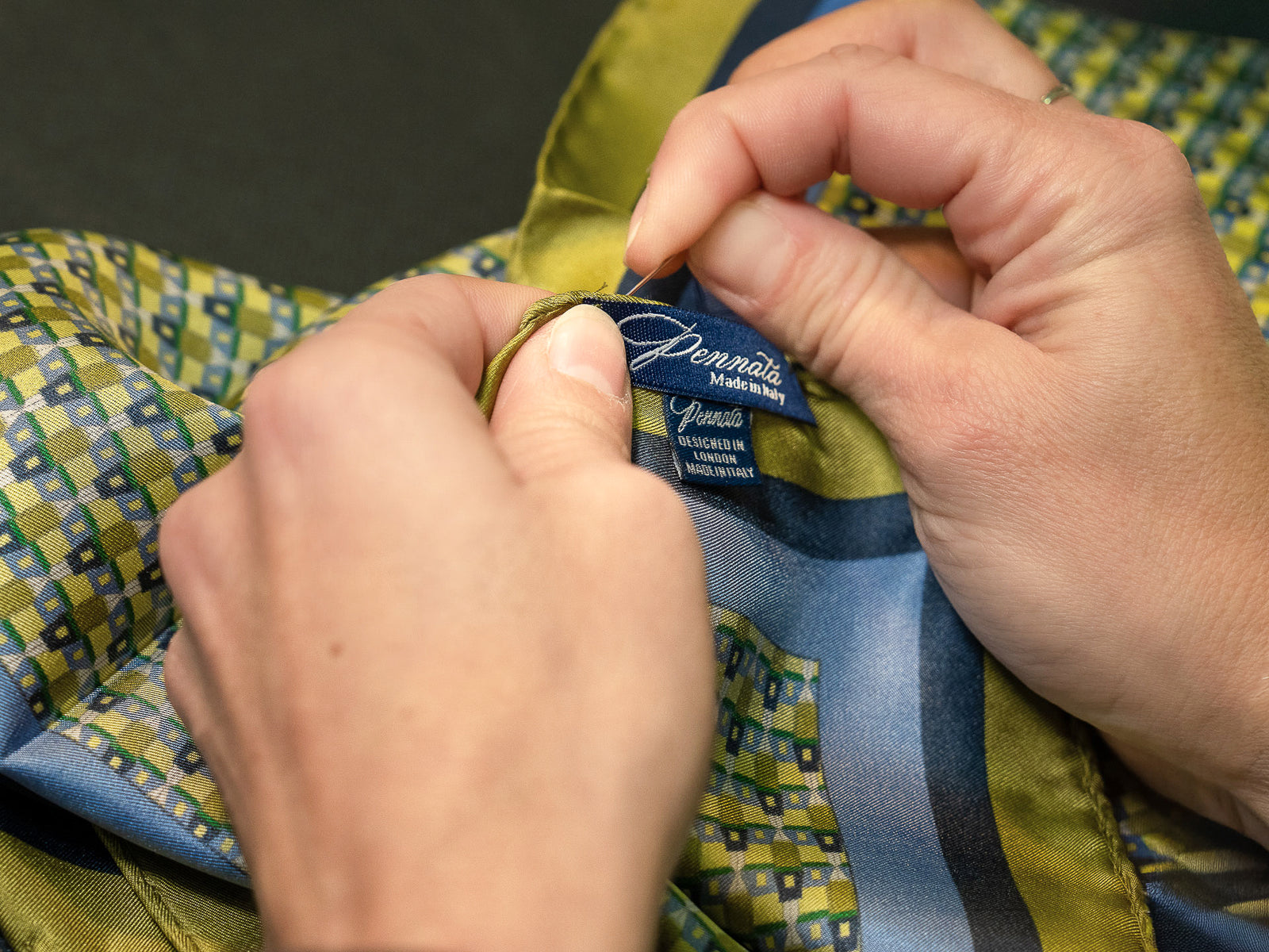 Close-up of hands holding a colorful fabric with a brand label.
